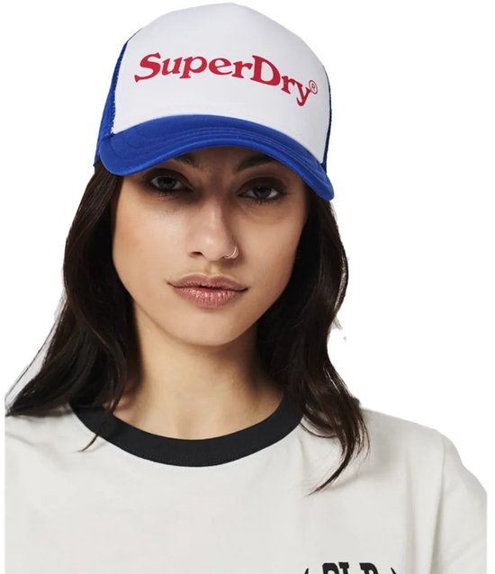 Casquette trucker Superdry blanche à mesh bleu sur modèle. Texte Superdry rouge.
