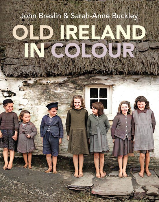 Boek 'Old Ireland in Colour' met 7 kinderen in traditionele kleding voor een stenen huis met rieten dak.