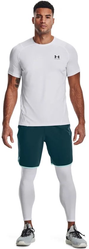 Man draagt witte korte mouwen sportshirt en witte sportlegging met blauw/groene shorts.