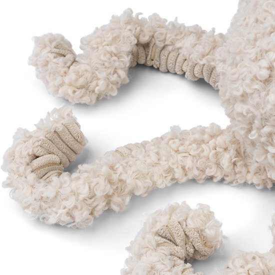 Close-up van de geribbelde, crèmekleurige tentakels van een octopusknuffel met teddy-stof.