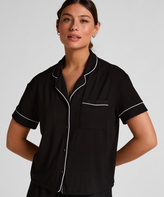 Model in zwart pyjamashirt met witte biesjes en borstzakje.