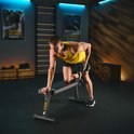 Man met gele tanktop doet dumbbell row op zwarte trainingsbank.