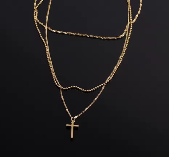 Gouden gelaagde ketting met kruishanger op een zwarte achtergrond.