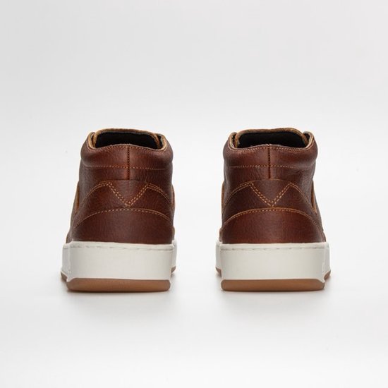 Achterkant van bruine leren mid-top sneakers met witte zolen.