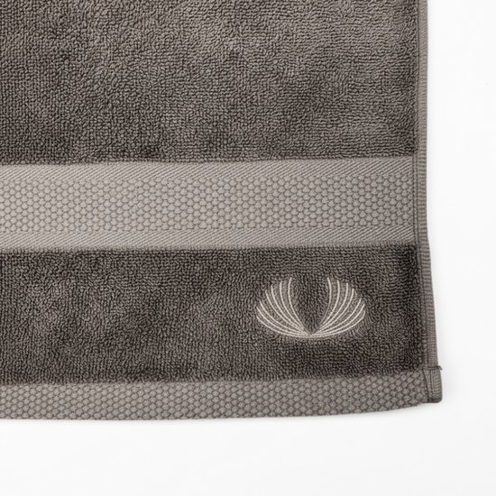 Grijze handdoek met decoratieve strepen en geborduurd logo.
