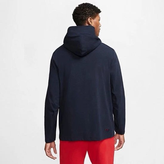 Donkerblauw Nike Tech vest, achterkant zichtbaar, met capuchon. Een persoon draagt het vest.