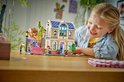 Meisje speelt met LEGO Friends Liann's Familiehuis, met roze dak en blauwe ramen.