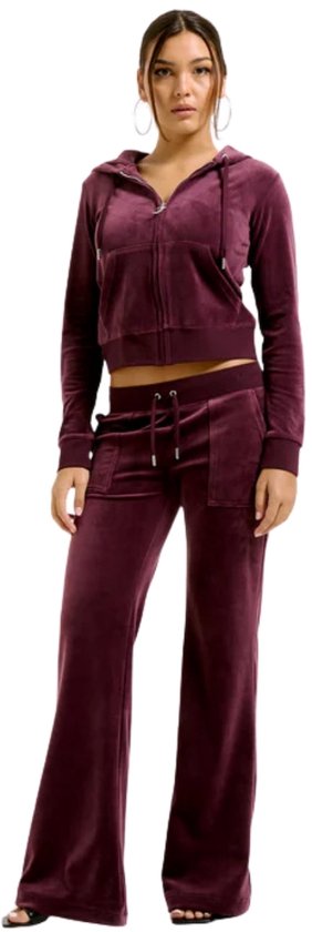 Model in paarse Juicy Couture velours joggingbroek en bijpassende cropped hoodie met capuchon en rits.