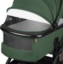 Close-up van de groene reiswieg van een kinderwagen met een wit zonnescherm en een gaasvenster.