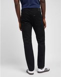 Man in donkerblauwe top en zwarte jeans, zicht van achteren. Draagt witte sneakers met strepen.