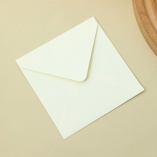 Gebroken witte vierkante envelop op een beige achtergrond.