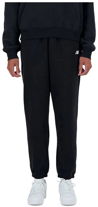 Zwarte New Balance joggingbroek met wit logo, gedragen met witte sneakers.