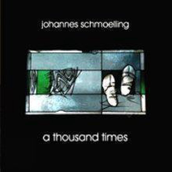 Een close-up van een glas-in-loodraam met de titel 'johannes schmoelling a thousand times'. Rechts staan ​​twee witte sandalen.