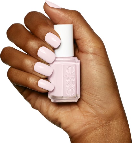 Donker getinte hand met zachtroze nagellak en een flesje Essie nagellak.