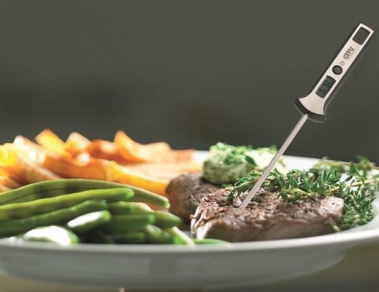 Gegrilde biefstuk op een bord met groenten en aardappelen, met een digitale thermometer.