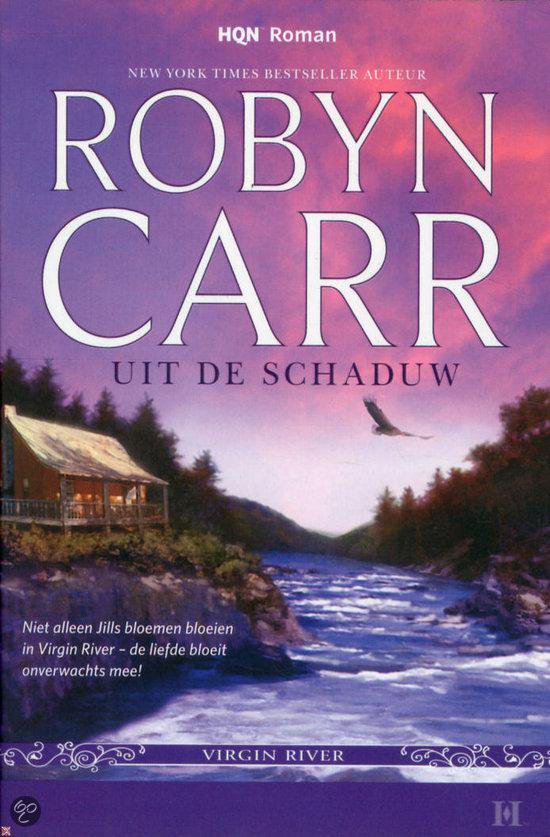 Boekcover met "UIT DE SCHADUW" door ROBYN CARR. Een landschap met een rivier en huisje.