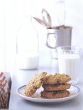 Stapel koekjes met rozijnen op een wit bord met blauwe rand, naast een glas melk.