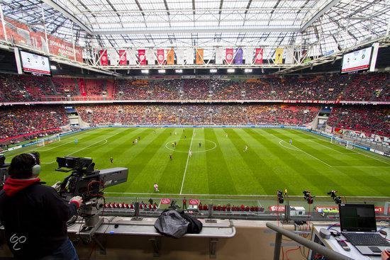 Een drukke voetbalwedstrijd in een vol stadion met veel publiek.