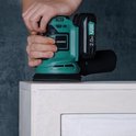 Handen schuren een wit meubel met een groene Vonroc excentrische schuurmachine met 2.0Ah 20V accu.