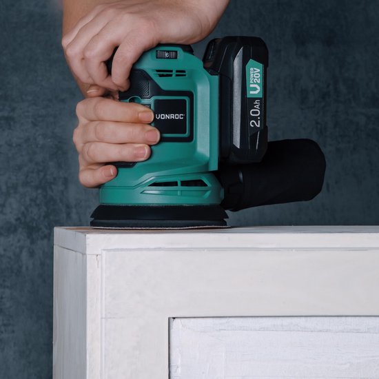 Handen schuren een wit meubel met een groene Vonroc excentrische schuurmachine met 2.0Ah 20V accu.