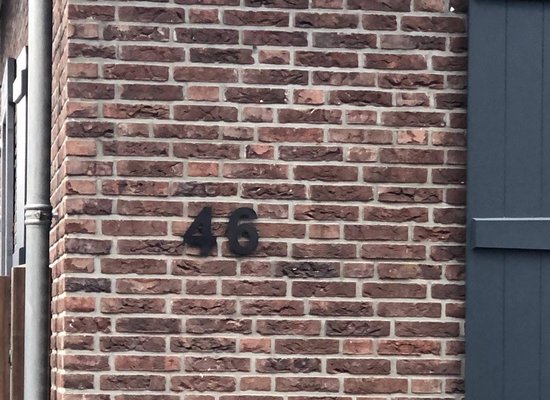 Huisnummer 46 op een rode bakstenen muur.