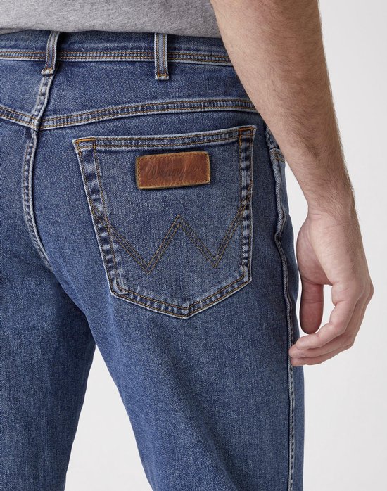 Achteraanzicht van een blauwe spijkerbroek met Wrangler logo op de achterzak.