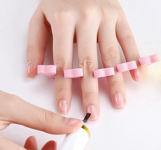 Écarteurs de doigts en feutre rose, tandis qu'une main applique du vernis à ongles.