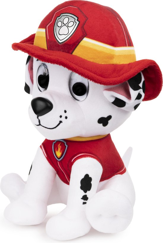 Zittende witte Dalmatische puppyknuffel met zwarte vlekken, draagt een rood brandweeruniform en een rode helm met een zilveren embleem. Zwarte ogen, glimlachende mond.