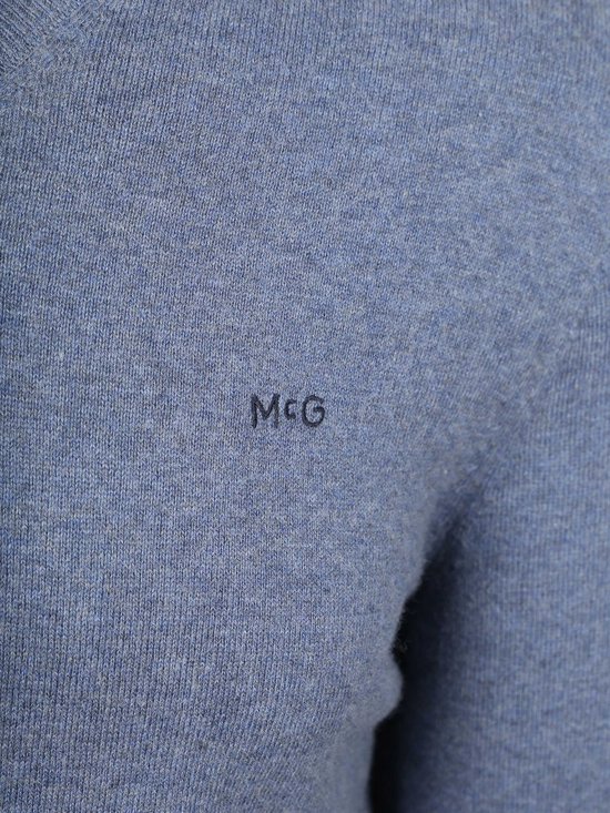 Detailopname van het geborduurde 'McG' logo op een blauwe McGregor trui.
