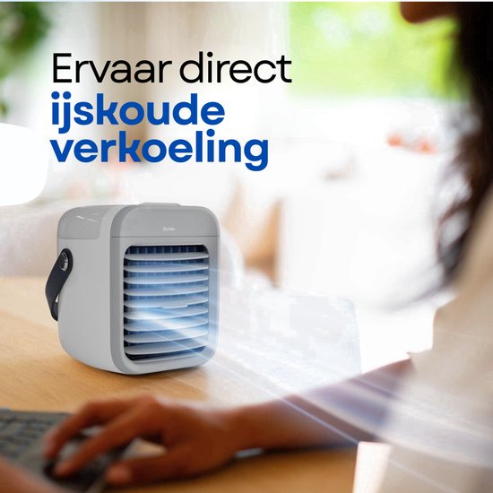 Wit en grijs mobiel aircoolertje op een bureau, met een vrouw die op een laptop typt.