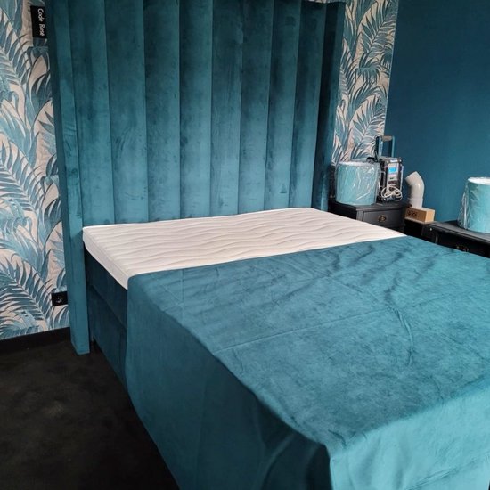 Luxe hotel boxspring met een hoog, gestoffeerd, 9-baans hoofdbord in de kleur lichtgrijs. De matrashoes is wit met horizontale ribbels.