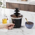 Zwarte Princess chocoladefontein met 3 lagen, met een hand die de draaiknop instelt.