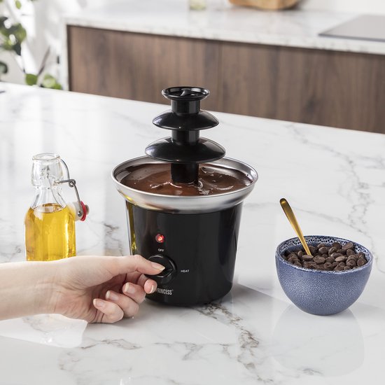 Zwarte Princess chocoladefontein met 3 lagen, met een hand die de draaiknop instelt.