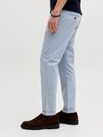 Zij-aanzicht van het onderlichaam van een man in een lichtblauwe pantalon met ruitpatroon en omgeslagen pijpen.
