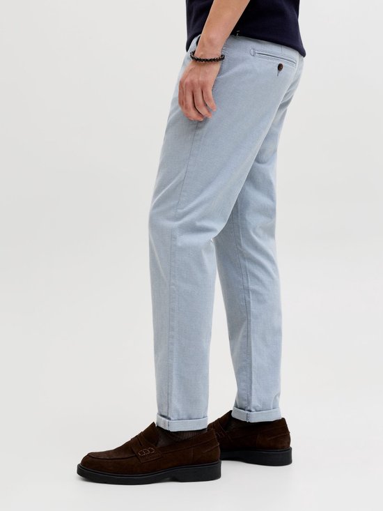 Zij-aanzicht van het onderlichaam van een man in een lichtblauwe pantalon met ruitpatroon en omgeslagen pijpen.