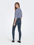Model in donkerblauwe skinny jeans, gezien van achteren. Gestreepte blouse met opgerolde mouwen.