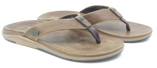 Twee bruine leren Reef teenslippers met Reef logo op de band.