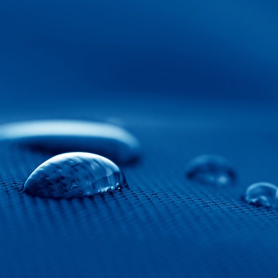 Close-up van blauwe stof met waterdruppels. Textuur van stof is zichtbaar.