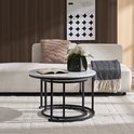 Twee ronde bijzettafels met marmerlook blad en zwart metalen onderstel. Eén tafel staat voor de bank, de ander er deels onder.