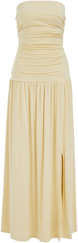 Een gele strapless maxi jurk met gerimpeld lijfje en hoge split, staand op witte achtergrond.