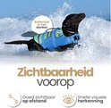 Zwarte labrador in blauw visvormig zwemvest met groene en paarse strepen, zwemmend in de golven.