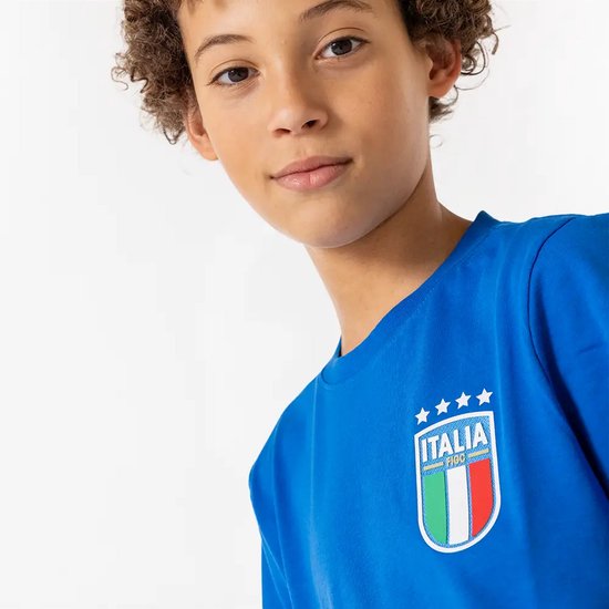 Close-up van een jongen met krullend haar die een blauw T-shirt draagt. Focus op het Italië-embleem.