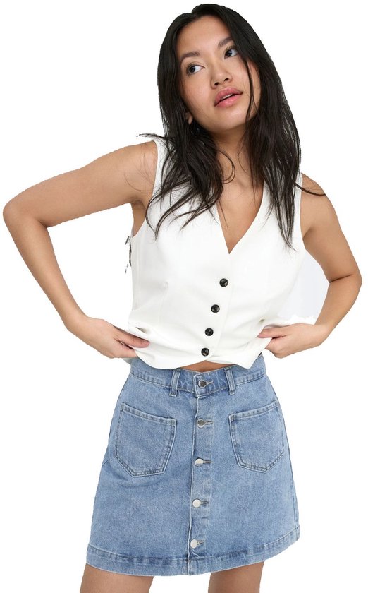 Model draagt een witte, mouwloze top met V-hals en zwarte knopen, gecombineerd met een lichtblauwe denim minirok met knoopsluiting.