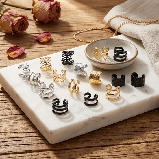 Veertien oorclips in zilver-, goud- en zwarttinten, met diverse designs, tentoongesteld op een marmeren plateau.