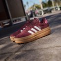 Bordeauxrode Adidas sneakers met witte strepen en dikke gum-zolen, buiten.