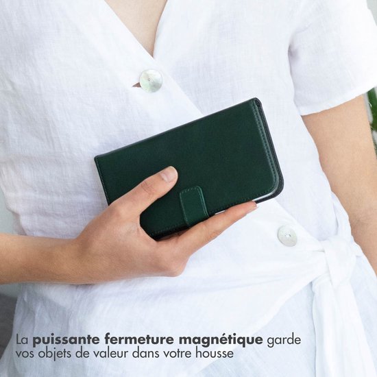 Close-up van een persoon met een witte top die een donkergroene boekhoes vasthoudt met de tekst 'La puissante fermeture magnétique garde vos objets de valeur dans votre housse'.