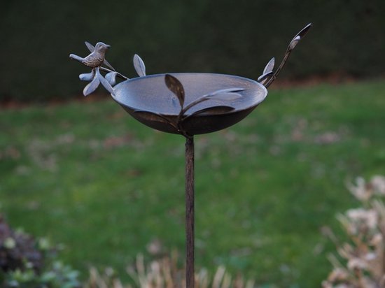 Donkerbruin metalen vogelbad op een tuinsteker, versierd met metalen bladeren en een vogeltje aan de rand.
