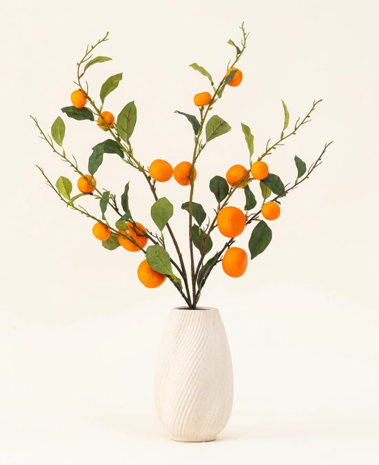 Een kunstboeket van mandarijnen met oranje vruchten en groene bladeren, geplaatst in een witte vaas.