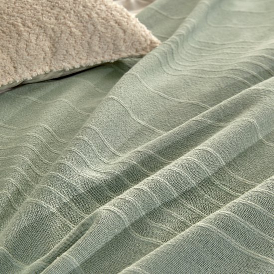 Een close-up van een lichtgroen plaid met subtiele witte strepen en kreukels.