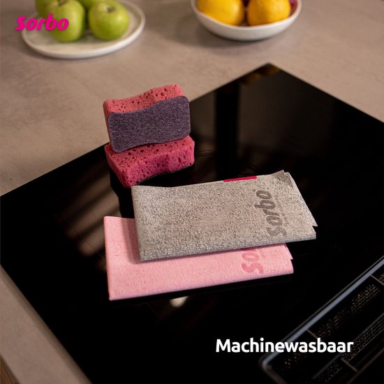 Twee roze en paarse sponzen en twee Sorbo microvezeldoeken, één grijs en één roze, op een zwarte kookplaat.